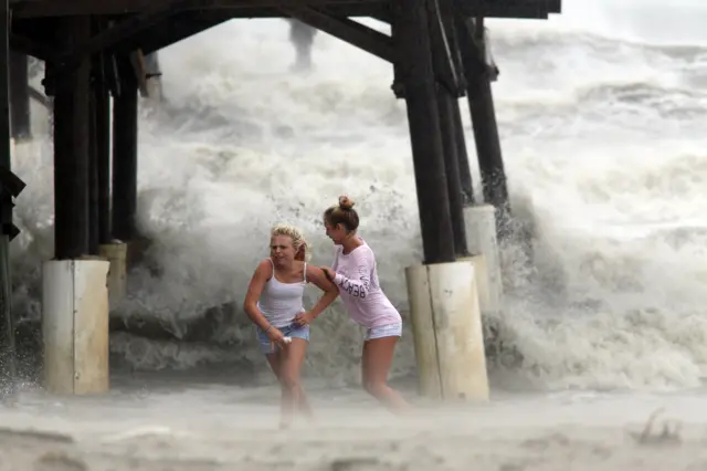 Kaleigh Black, 14, left, and Amber Olsen, 12, run for cover as a squall with rain and wind from the remnants of Hurricane Matthew pelt them as they explore the Cocoa Beach Pier.