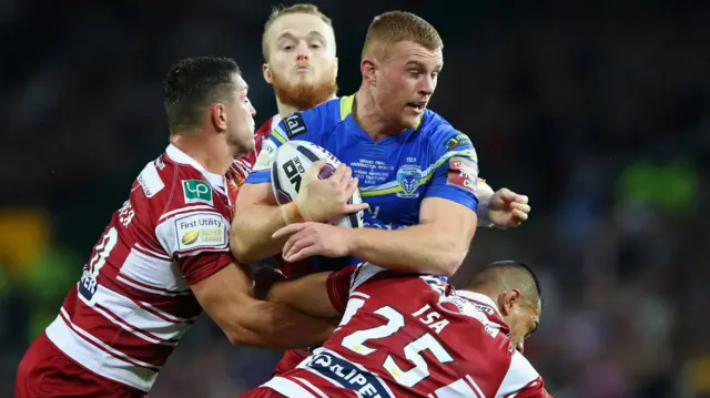 Jack Hughes of Warrington Wolves is tackled by Ben Flower and Willie Isa