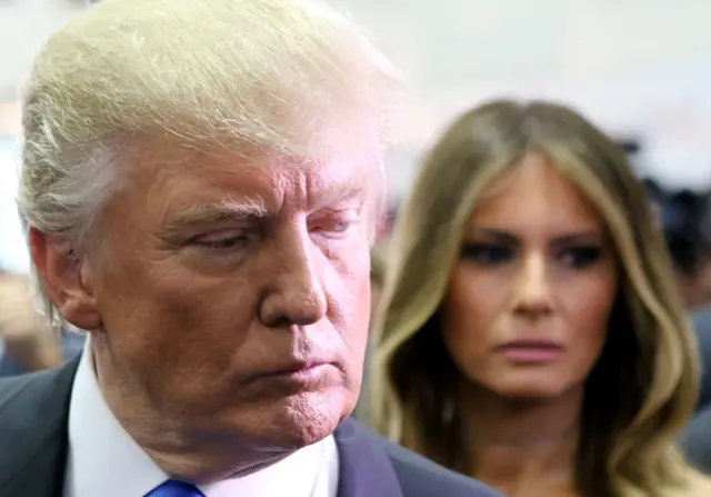 Republican presidential nominee Donald Trump speaks to the media in the spin room as wife, Melania Trump (R) looks on during the Presidential Debate in Hempstead, New York.