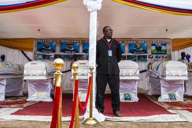 Man stands guard before six coffins containing bodies of killed opposition supporters