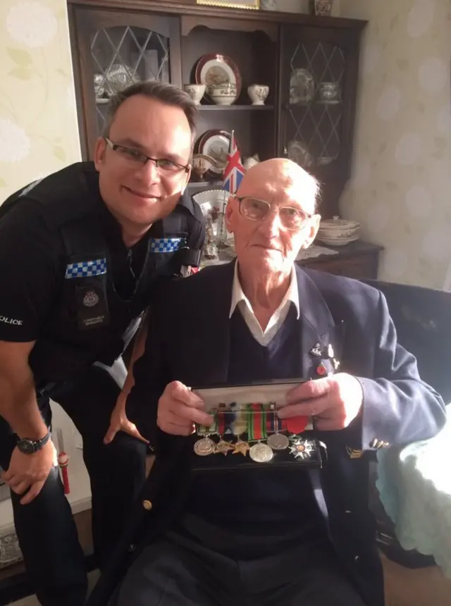 War veteran Jack Roberts holds his medals with a police officer