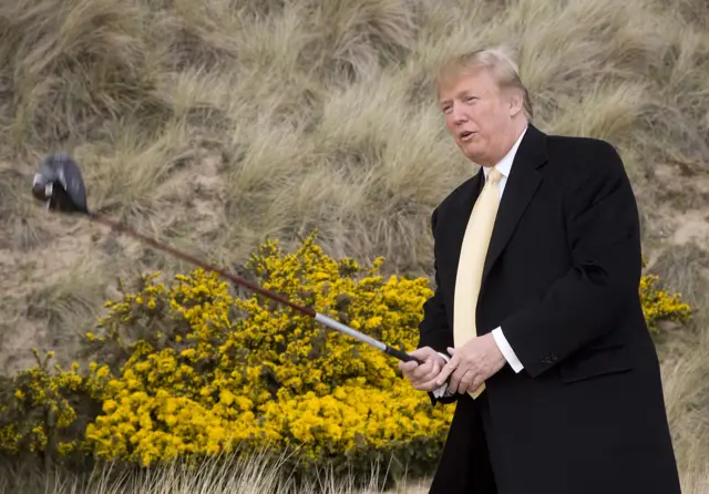 Donald Trump holds a golf club at his course in Scotland