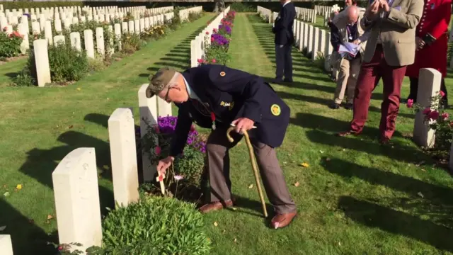 Verdun Hayes placing poppy on war grave