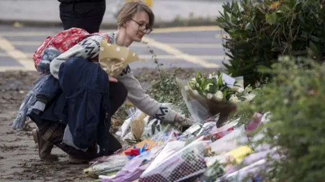 A member of the public lays flowers at scene where a tram derailed in Croydon