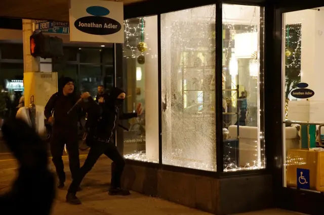 Portland, Oregon protesters break a shop window
