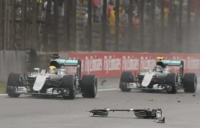 Hamilton and Rosberg drive past the debris from Raikkonen's crash