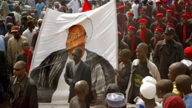 Black-shirted followers of a hardline Shiite Muslim sect carry a banner depicting Ibrahim Zakzaky, a Nigerian Shiite radical who wants to set up an Islamic Republic, as thousands of Nigerian Muslims protest 10 February, 2005 in the northern city of Kano after weekly prayers on Friday to condemn cartoon drawings of the Prophet Mohammed published in European newspapers