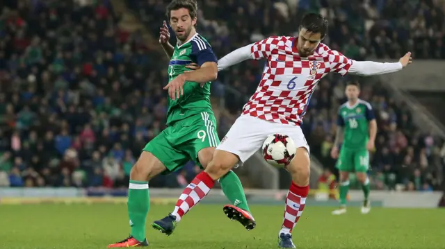 Will Grigg challenges for the ball