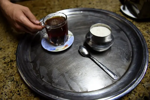 An Egyptian man serves a cup of tea with sugar at a cafe in the capital Cairo on October 26, 2016.