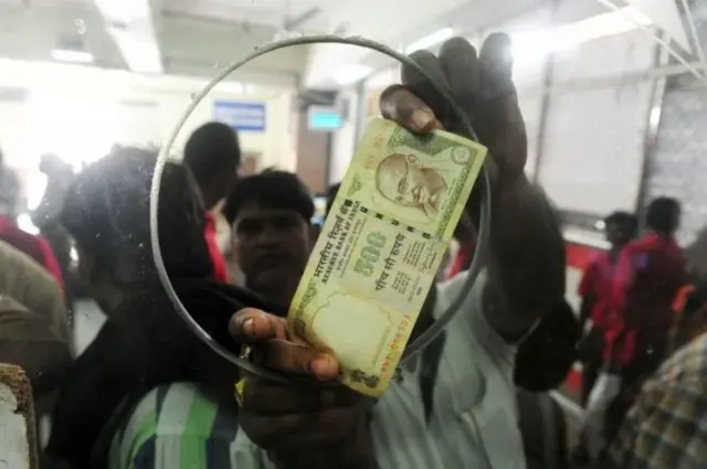 Man holding up 500 rupee note at bank