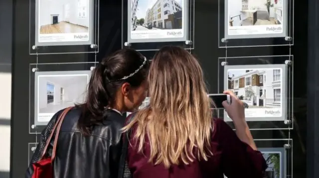 Young women looking at estate agent's window