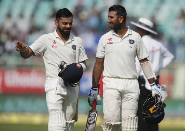 Kohli and Pujara laugh as they leave the ground after a dog got on the pitch