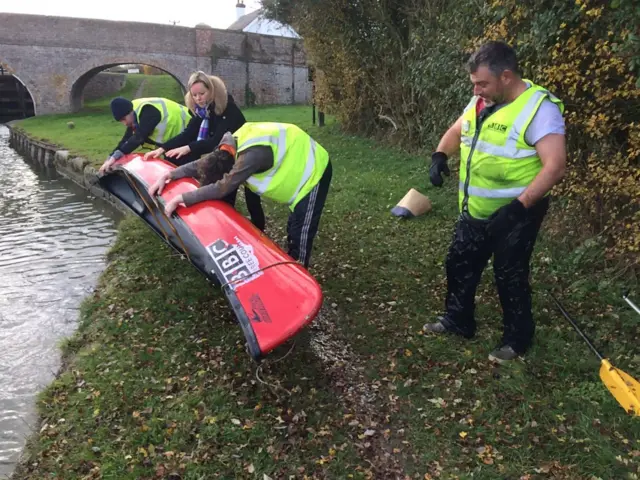 Andy Collins dripping wet as BBC team tips water out of his canoe