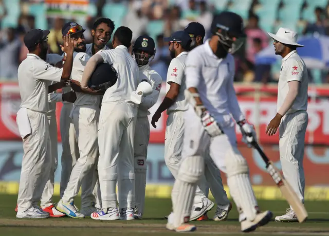 India players celebrate as England's Moeen Ali walks off the pitch after being dismissed