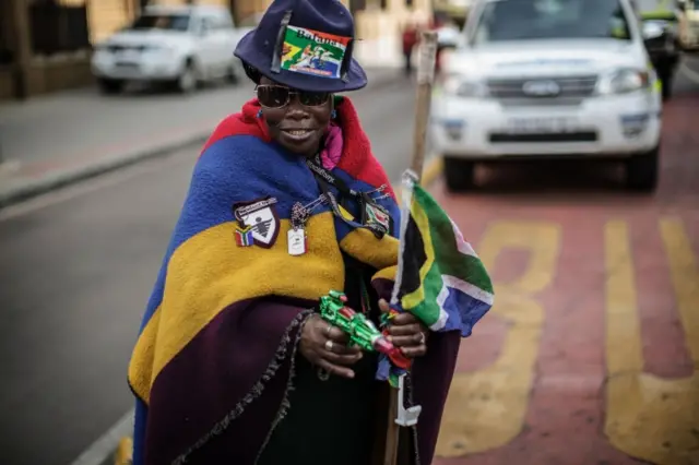 An elderly South African woman holding a water gun as she takes part in a demonstration