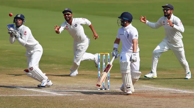 India"s Wriddhiman Saha (L) takes a catch to dismiss England"s Ben Duckett.