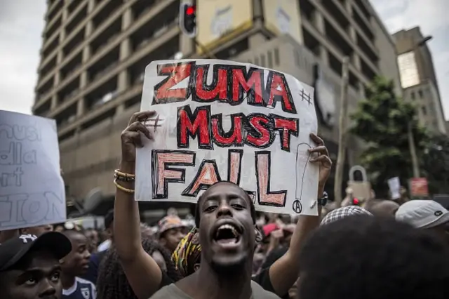 A student holds a placard reading 'A placard with 'Zuma must fall' outside the Luthuli House, the ANC headquarters, on October 22, 2015, in Johannesburg