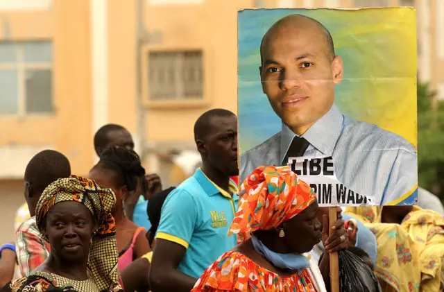 Supporters of Karim Wade wield a poster of the former minister