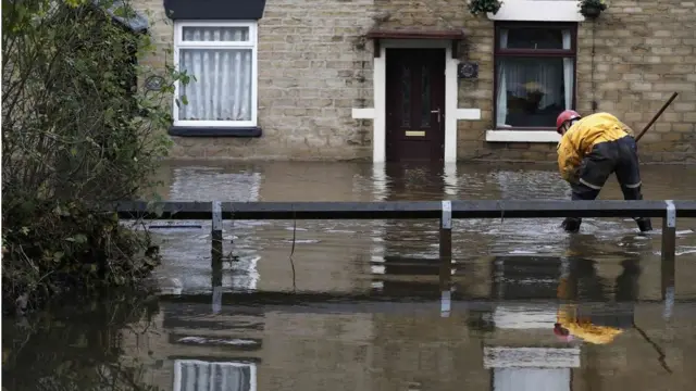 An emergency services worker stands in flood water in Stalybridge