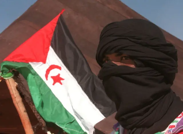 A Sahrawi refugee poses near a Sahrawi Democratic Arab Republic flag in Samra's refugees camp 30 November near Tindouf, Algeria