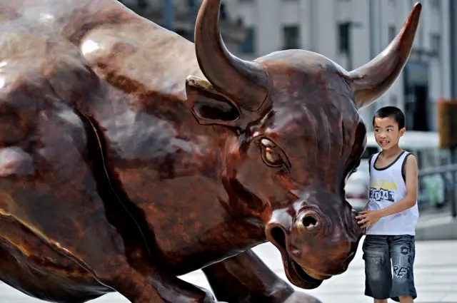 A Chinese boy stands next to a bull