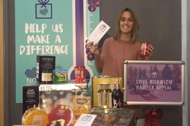 Woman stands behind a display of goods, for hampers