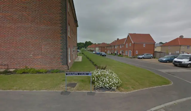 Triumph Court, showing road sign, properties and parked vehicles