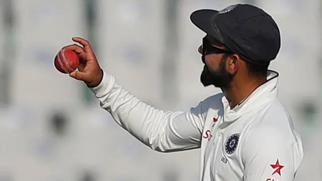 Virat Kohli inspects the ball