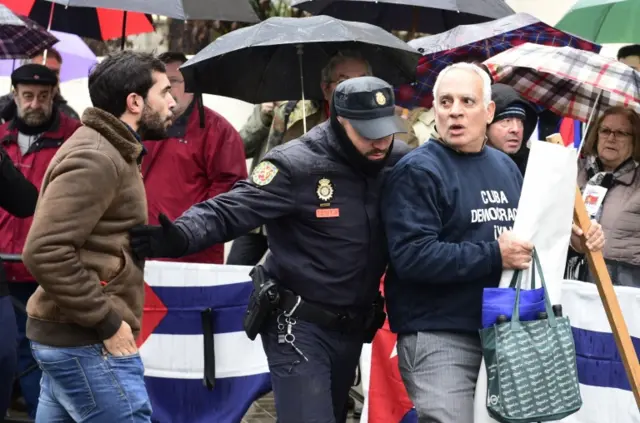 A police officer separates pro and anti Castro demonstrators in front of Cuba"s embassy in Madrid on November 26, 2016