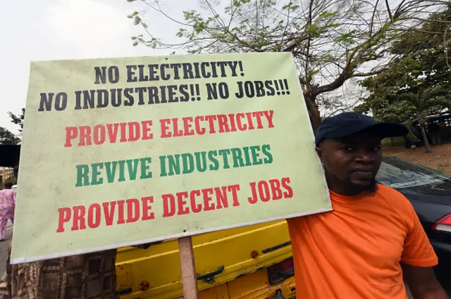 A man holds a placard reading 'No electricity! No industries!! No jobs!!! Provide electricity, revive industries, provide decent jobs' during a demonstration to protest against the 45 percent raise of electricity prices on February 8, 2016 in Lagos