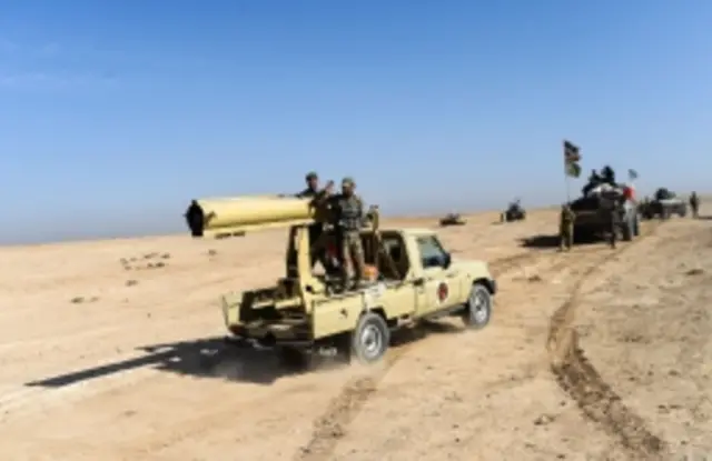 Members of Iraqi pro-government forces drive towards the South of Mosul