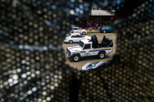 Anti-riot police officers sit in the back of a police vehicle as they patrol during a demonstration by opposition parties against the introduction of bond notes as a currency in Harare, on November 30, 2016