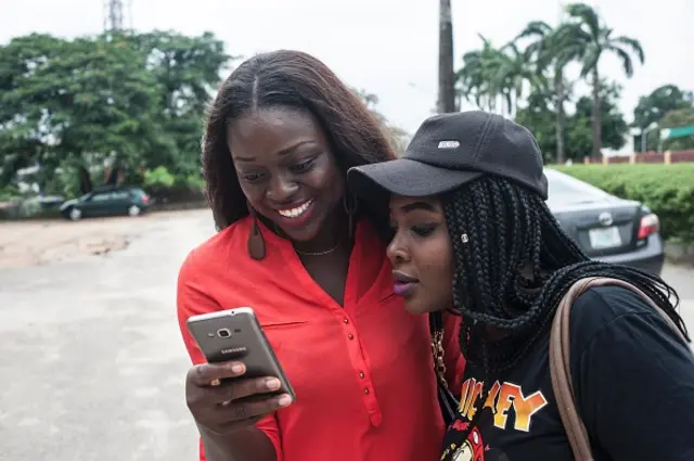 Esther Mustapha (L) and her friend Oyinbecks Olajide (R) use the Pokemon Go application on their mobile on the campus grounds of the University of Lagos on July 14, 2016.