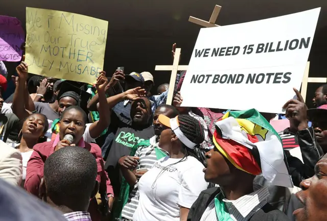 People hold crosses and banners during a protest against the introduction of new bond notes in Zimbabwe