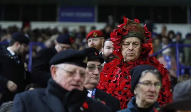 A man in the stands wearing a poppy suit