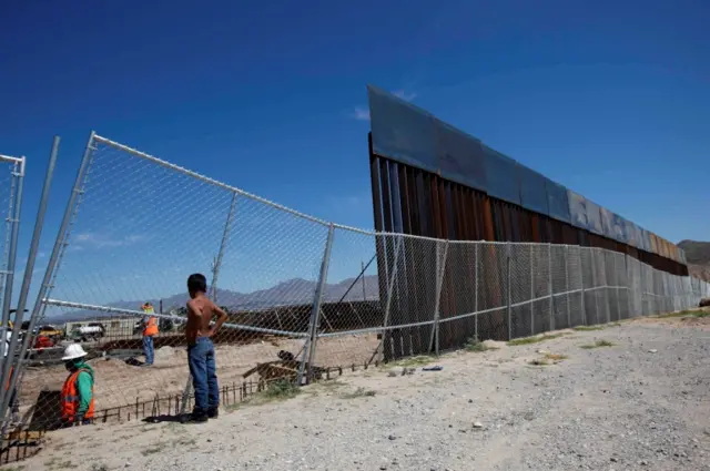 A boy looks as U.S. workers build a section of the U.S.-Mexico border wall