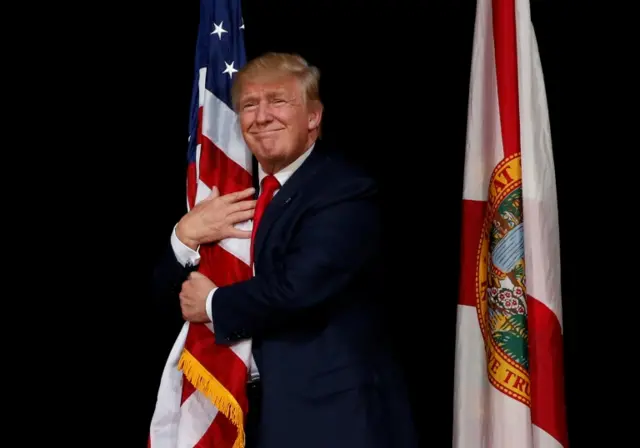 Donald Trump, republican presidential candidate, hugs an American flag.