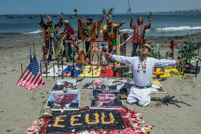 Shamans perform a ritual of predictions for the upcoming US election with posters of presidential candidates Donald Trump and Hilary Clinton at the Agua Dulce beach in Lima.