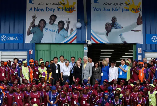 Former US president Bill Clinton (centre R) and his wife, US Secretary of State Hillary Clinton (centre L), pose with workers at the grand opening ceremony of the new Caracol Industrial Park in Caracol, Haiti, in 2012.