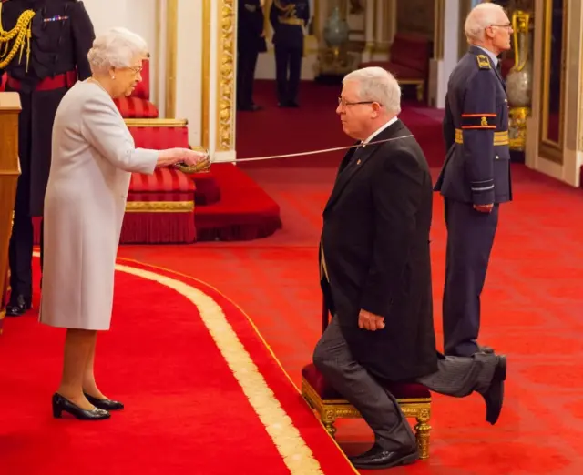 Sir Patrick McLoughlin being knighted by The Queen