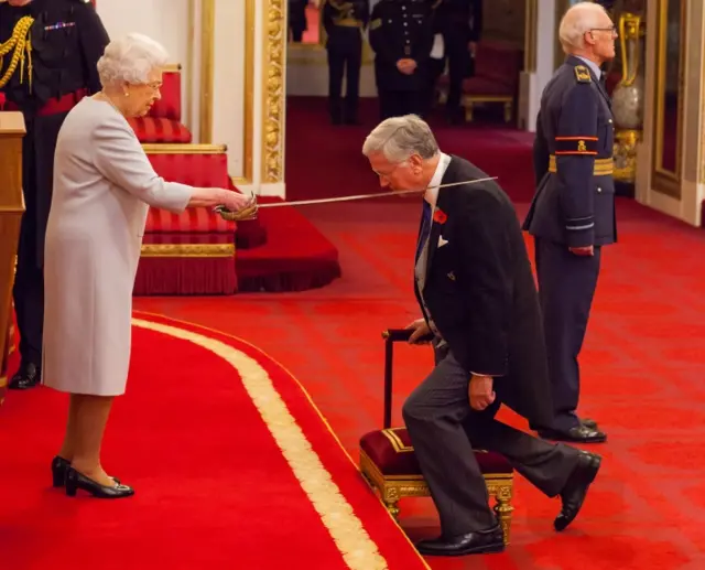 Sir Michael Fallon being knighted by The Queen