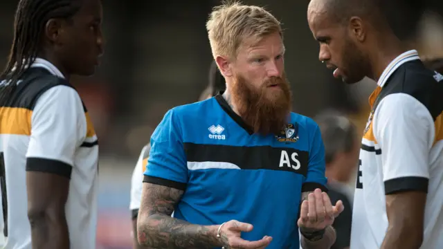 Bearded man speaking to footballer on pitch