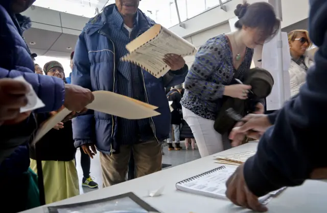 Voters receive their ballots at the Brooklyn Museum polling site, Tuesday Nov. 8, 2016, in Brooklyn, N.Y.