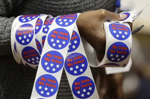 Iris Pettigrew carries voting stickers for voters after they cast their ballots on 8 November.