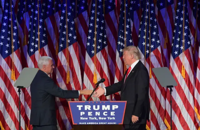 Donald Trump (R) shakes hands with Republican candidate for Vice President Mike Pence speak during election night at the New York Hilton Midtown in New York on November 9, 2016