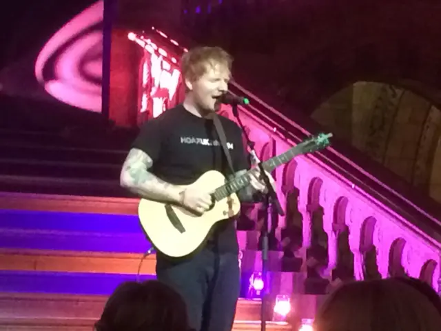 Ed Sheeran on steps of stage, with guitar