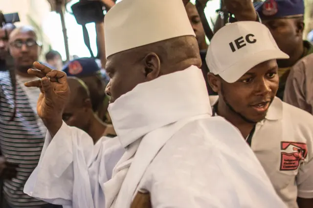 President Yahya Jammeh, dressed in white robes, looks at his marble before voting