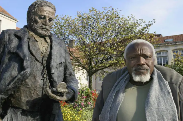 Ousmane Sow standing next to his sculpture of the author Victor Hugo