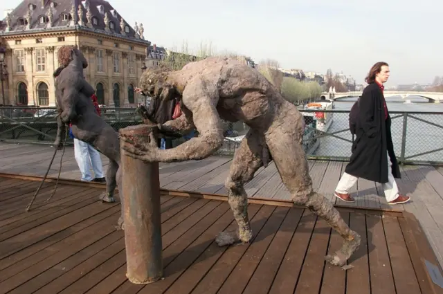 A man walks past some of the sculptures by Senegalese sculptor Ousmane Sow exhibited on the famous Ponts des Arts 18 March 1999 in Paris