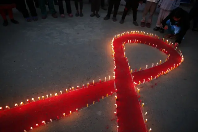 Nepalese women and children light candles on the eve of World AIDS Day